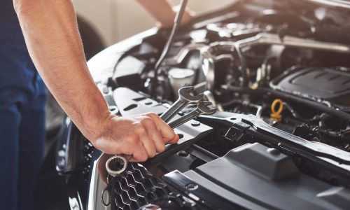 Picture showing muscular car service worker repairing vehicle.